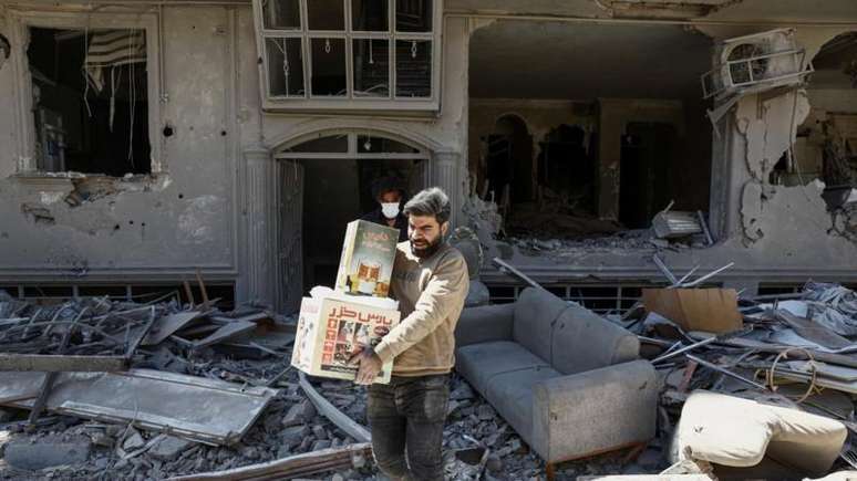 Homem carrega caixas de uma casa danificada por ataques em Teer&atilde;, capital do Ir&atilde;, na segunda-feira (30/3)