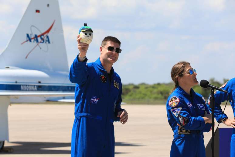 Jeremy Hansen segura a mascote lunar, Rise, que funciona como indicador de gravidade zero.