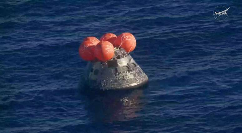 A c&aacute;psula Orion libera quatro flutuadores redondos de cor laranja enquanto repousa sobre a superf&iacute;cie do mar