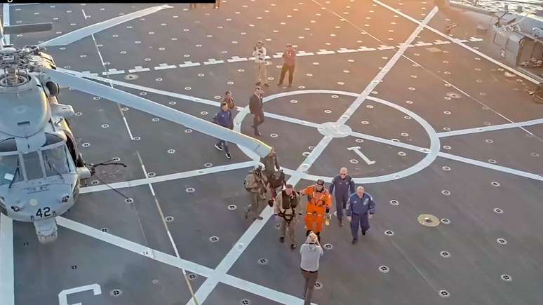 O comandante Reid Wiseman sobe a bordo do navio de resgate ap&oacute;s ser retirado da c&aacute;psula Artemis II pela equipe de resgate no Oceano Pac&iacute;fico