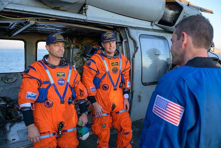 O comandante Reid Wiseman (&agrave; esquerda) e o astronauta Jeremy Hansen s&atilde;o recebidos pelo administrador da NASA, Jared Isaacman, a bordo do John P. Murtha.
