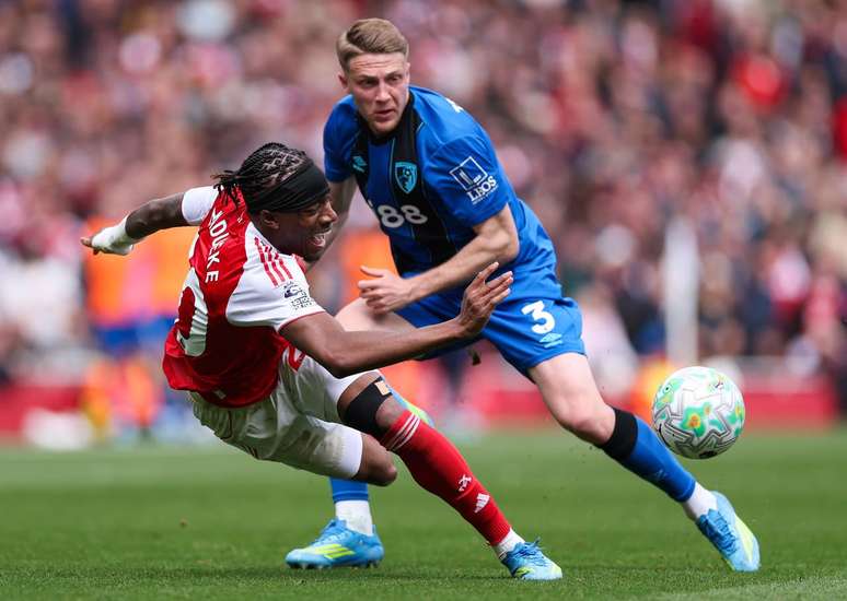 Madueke, do Arsenal (de vermelho) trope&ccedil;a durante disputa com Adrien Truffert.