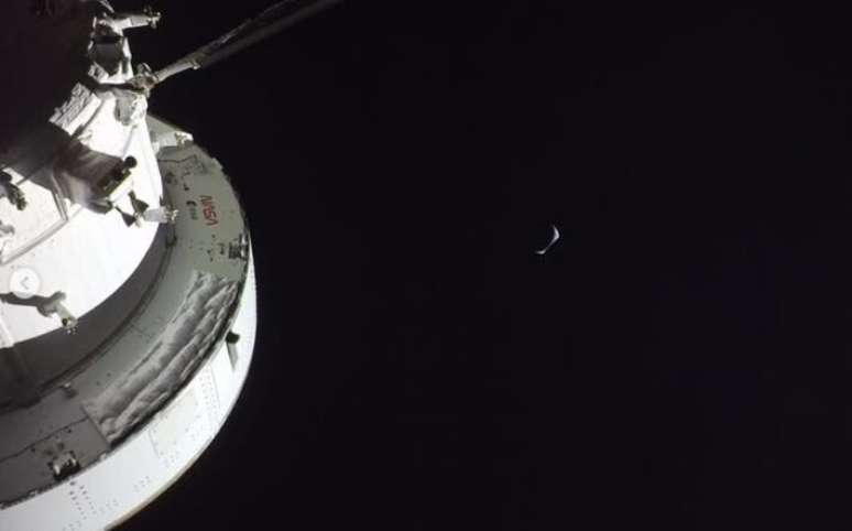 A sonda Orion, que levou os quatro astronautas ao espa&ccedil;o, aparece na imagem; a Terra, encoberta parcialmente pela Lua, aparece ao fundo