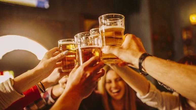 Pessoas brindam com copos de cerveja