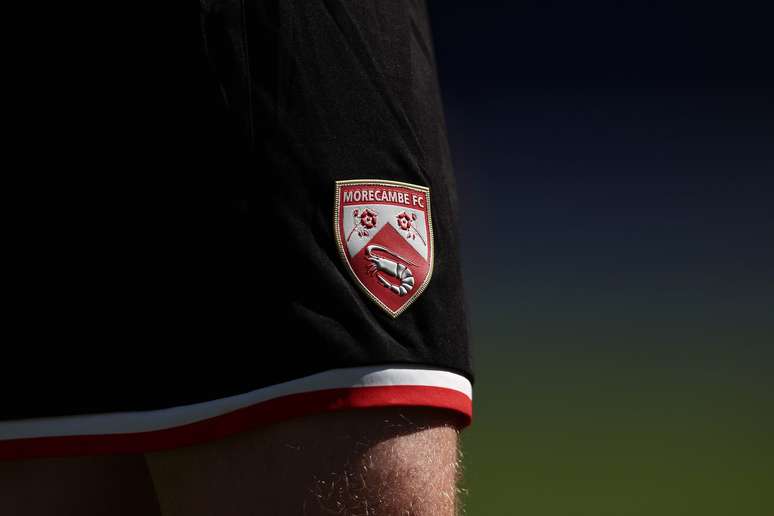 O Escudo do Morecambe FC traz um camar&atilde;o, s&iacute;mbolo da tradi&ccedil;&atilde;o pesqueira da cidade inglesa. 
