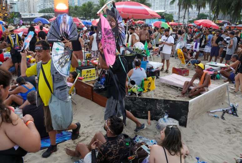 Vendedores de leques caminham entre os f&atilde;s de Shakira em Copacabana neste s&aacute;bado, 2.