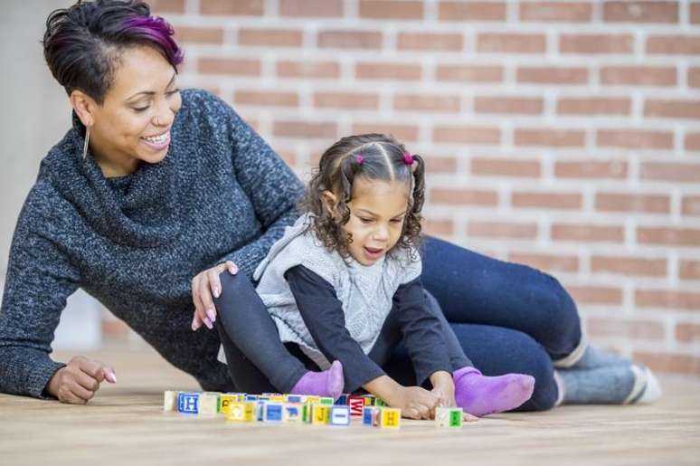 Uma m&atilde;e brincando com a filha no ch&atilde;o