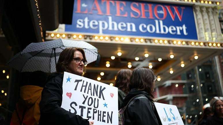 F&atilde;s reunidos do lado de fora do Teatro Ed Sullivan, em Nova York, com cartazes de agradecimento ao apresentador Stephen Colbert