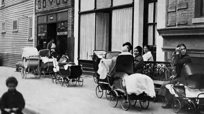 Mulheres e homens sentados com carrinhos de beb&ecirc; em frente &agrave; Cl&iacute;nica Sanger na Amber Street, no Brooklyn, Nova York, em outubro de 1916