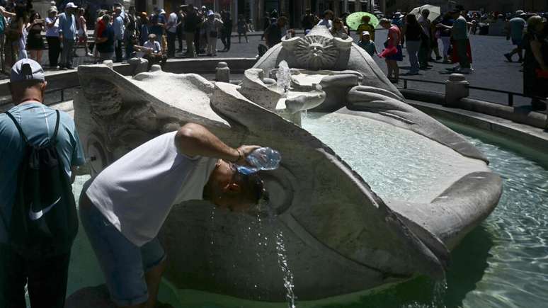 Um homem se refresca na fonte Barcaccia, perto da Escadaria da Pra&ccedil;a de Espanha, durante uma onda de calor no in&iacute;cio da temporada em Roma, em 26 de maio de 2026.