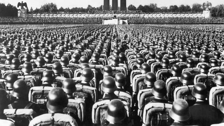 Tropas em posi&ccedil;&atilde;o de sentido enquanto Hitler faz um discurso em Nuremberg, em 1936