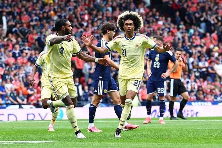 Chong (&agrave; direita) comemora seu gol para Cura&ccedil;ao. Ao seu lado, Leoc&aacute;dio, que seria expulso, o que facilitou a virada e a goleada escocesa.