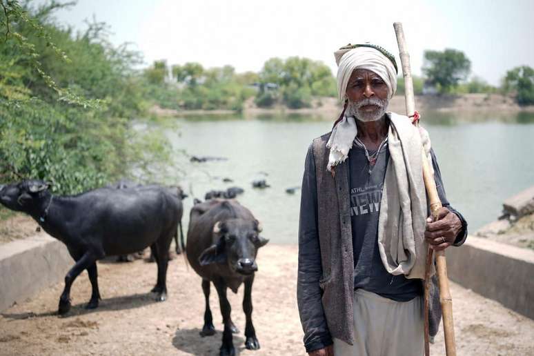 Rameshwar Yadav, criador de b&uacute;falos, usa um xale e roupas de inverno apesar do calor de 46&ordm;C.