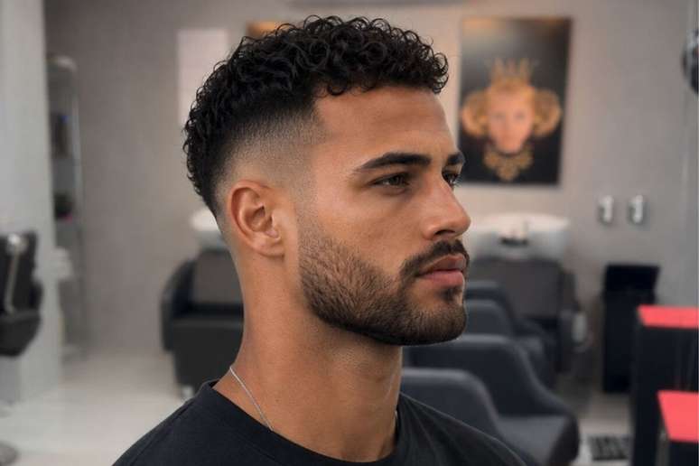 Homem corte degrad&ecirc; cacheado, barba e olhando para frente