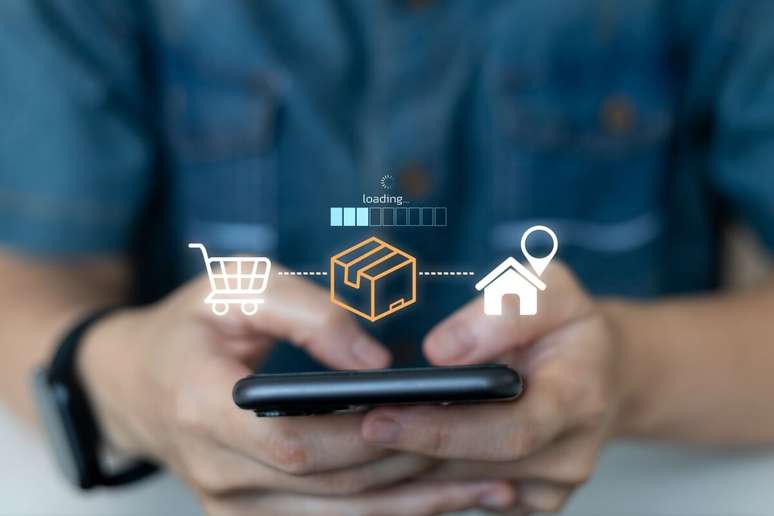 M&atilde;o segurando um celular com ilustra&ccedil;&atilde;o de compra e entrega online projetada acima da tela