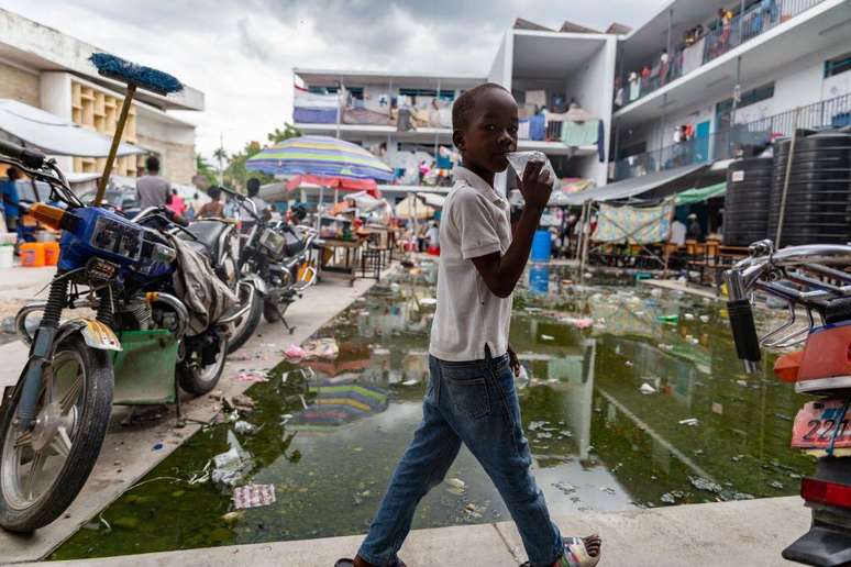 Uma crian&ccedil;a caminha pelo p&aacute;tio de um campo de refugiados em Porto Pr&iacute;ncipe, no Haiti, para onde milhares de pessoas fugiram ap&oacute;s serem for&ccedil;adas a deixar suas casas devido &agrave; viol&ecirc;ncia de gangues, em meio &agrave; falta de abrigo, comida, &aacute;gua pot&aacute;vel e servi&ccedil;os b&aacute;sicos. Imagem de 2024