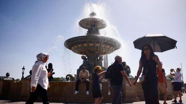 V&aacute;rias pessoas andando nas ruas da Fran&ccedil;a, pr&oacute;ximo de uma fonte