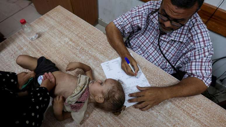 Uma menina palestina &eacute; examinada por um m&eacute;dico no Hospital dos M&aacute;rtires de Al-Aqsa, em Deir Al-Balah, na regi&atilde;o central da Faixa de Gaza, em 18 de agosto de 2024.