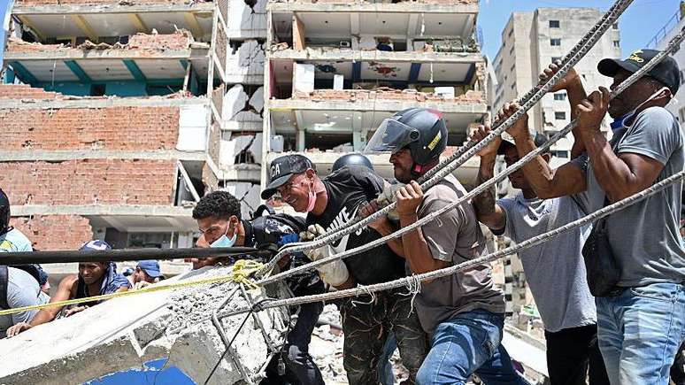 Moradores removem manualmente peda&ccedil;os de concreto durante as opera&ccedil;&otilde;es de resgate