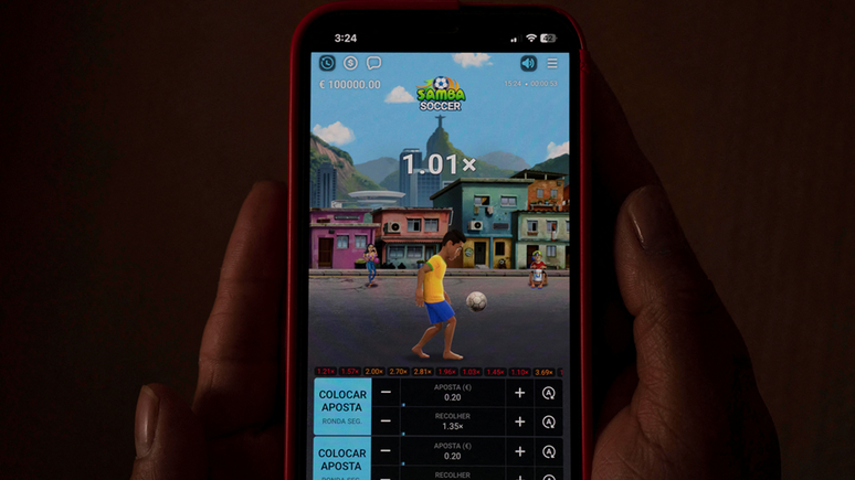 Pessoa segura celular com o slot game Samba Soccer na tela