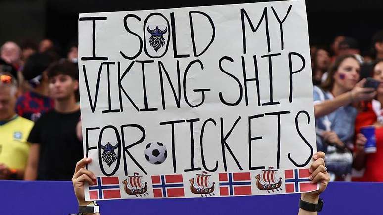 Um torcedor da Noruega exibe uma placa dizendo que vendeu seu navio viking para comprar ingressos para a partida durante a Copa do Mundo da FIFA de 2026.