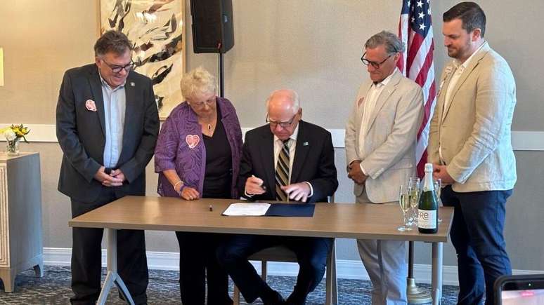 Anita LeBrun ao lado do governador de Minnesota, Tim Walz, na cerim&ocirc;nia de assinatura da nova lei na casa de repouso onde ela vive