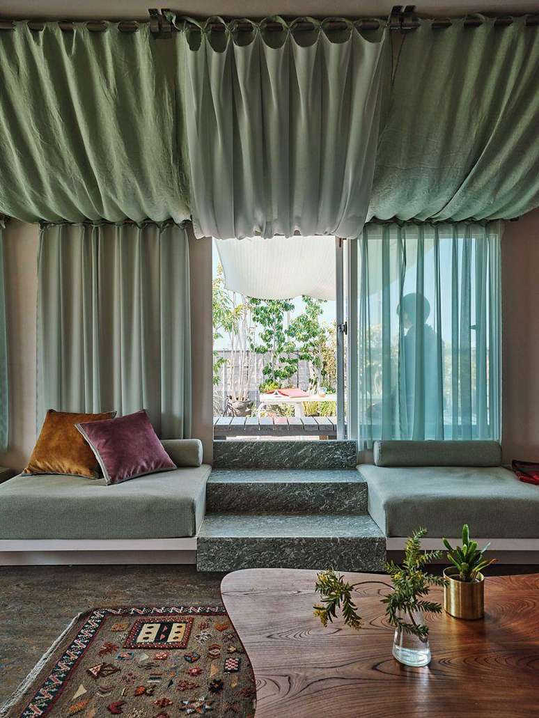 Porta de vidro no c&ocirc;modo de uma casa com sa&iacute;da para o jardim, com grandes cortinas