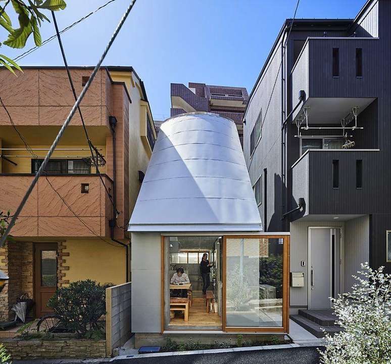 Casa espremida entre dois edif&iacute;cios no meio da cidade, com teto inclinado