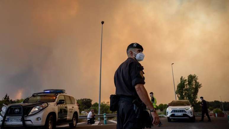 Um agente da Guarda Civil usa uma m&aacute;scara de prote&ccedil;&atilde;o enquanto a fuma&ccedil;a de um inc&ecirc;ndio florestal obscurece o c&eacute;u em Cenicientos, Madri, Espanha.