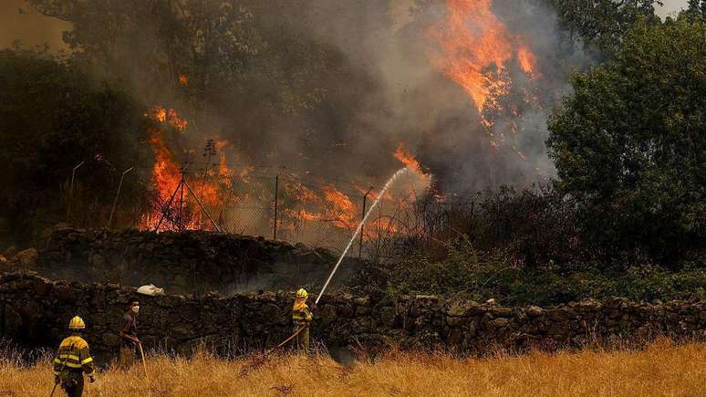 Bombeiros e civis tentam apagar um inc&ecirc;ndio florestal &agrave; medida que ele se aproxima de uma casa na prov&iacute;ncia espanhola de &Aacute;vila