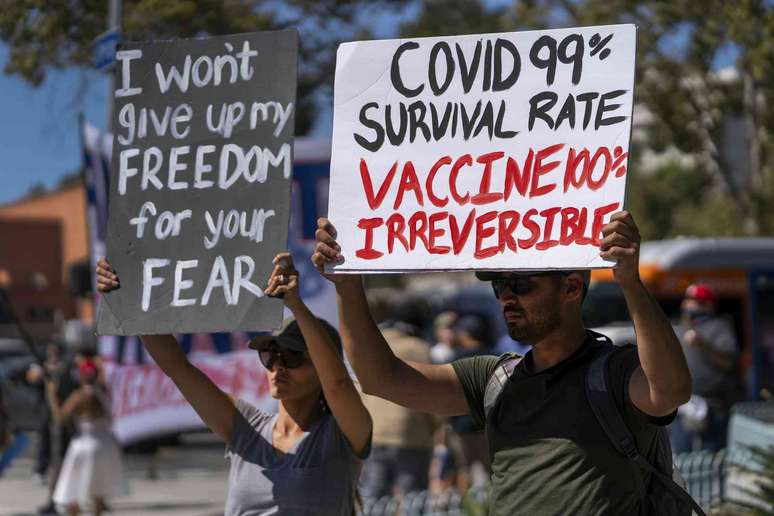 Manifestantes seguram cartazes com os dizeres ' N&atilde;o vou abrir m&atilde;o da minha liberdade por causa do seu medo&rsquo; e &lsquo;COVID: taxa de sobreviv&ecirc;ncia de 99% / vacina: 100% permanente&rsquo;