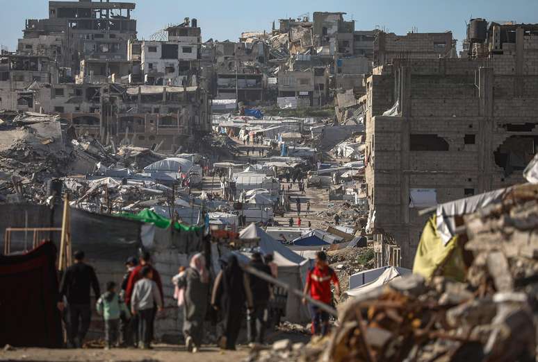 Palestinos caminham entre as ru&iacute;nas do bairro de Al Tuffah, na zona leste da Cidade de Gaza, em meio ao cessar-fogo entre Israel e o Hamas.