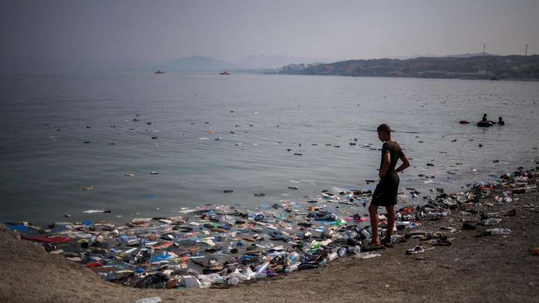 Um migrante observa os t&ecirc;nis na &aacute;gua ap&oacute;s as travessias em massa de migrantes a p&eacute; e por mar, do Marrocos para o territ&oacute;rio espanhol.