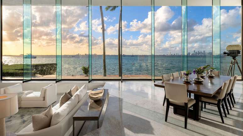 Sala da casa de John Daveney em Key Biscane, com duas enormes janelas de vidro e a cidade de Miami ao fundo
