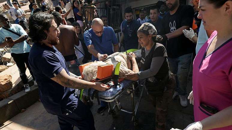 Mulher &eacute; carregada em uma maca ap&oacute;s ser resgatada de um pr&eacute;dio que desabou devido ao terremoto em Cali