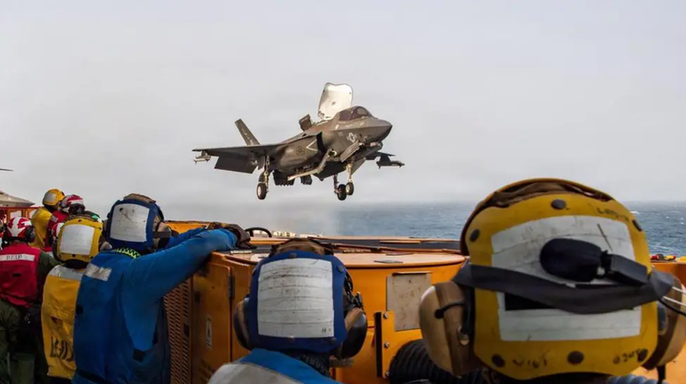 Militares americanos a bordo do navio de assalto anf&iacute;bio USS Boxer observam um ca&ccedil;a americano em voo. Foto de arquivo.