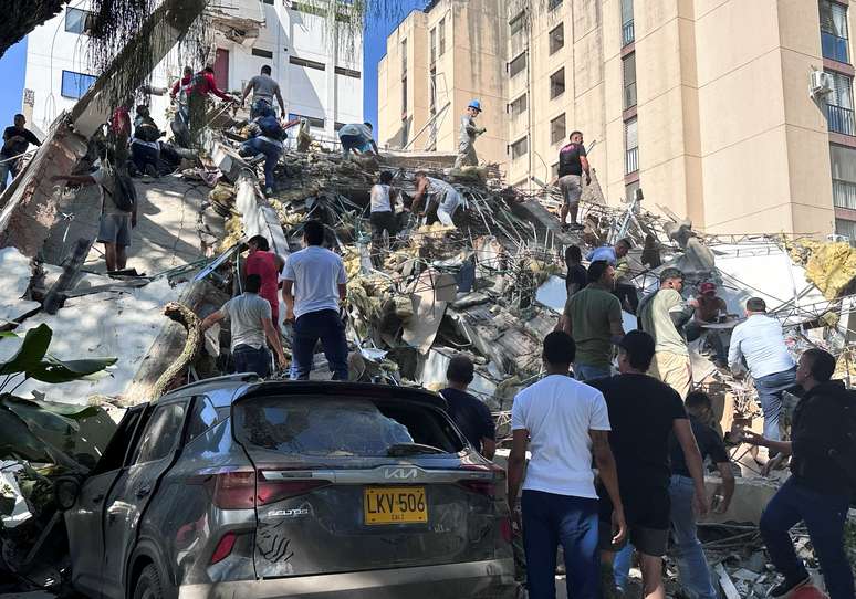 Moradores vasculham os escombros de um pr&eacute;dio que desabou ap&oacute;s um terremoto, em Cali, na Col&ocirc;mbia - 10 de agosto de 2026