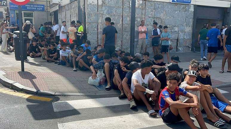 Os menores estrangeiros fazem fila diante de uma delegacia de pol&iacute;cia de Ceuta para serem identificados e iniciar seu acesso aos servi&ccedil;os de acolhimento