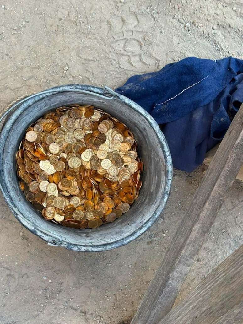 O balde ficou cheio de moedas de ouro encontradas na parede da propriedade. Os oper&aacute;rios avisaram a pol&iacute;cia assim que encontraram o tesouro.