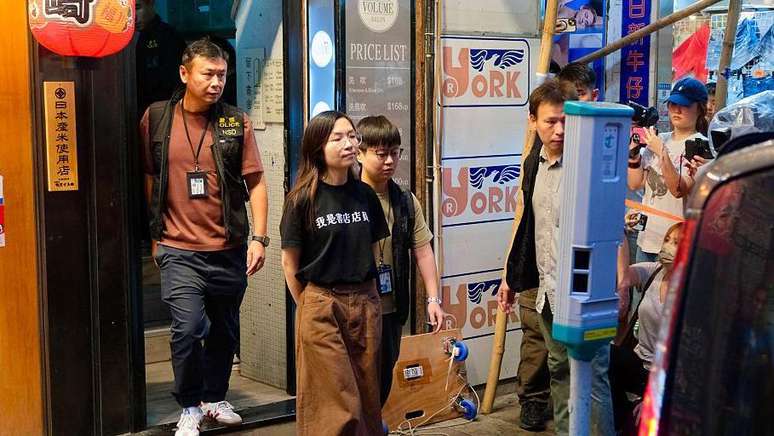 A pol&iacute;cia escolta uma funcion&aacute;ria para fora da livraria Have a Nice Stay, cuja camiseta dizia "Sou funcion&aacute;rio de uma livraria"