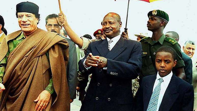 Em 2001, o rei Oyo (dir.), ent&atilde;o com nove anos, recebeu o l&iacute;der l&iacute;bio Muammar Gaddafi (esq.) no reino de Tooro, juntamente com o presidente ugandense Yoweri Museveni (centro)