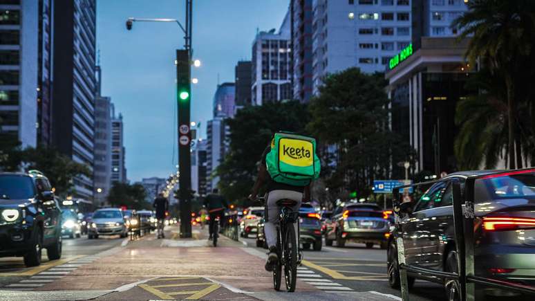 Ciclista com bag da Keeta andando em ciclovia da paulista no final de tarde