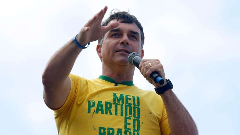 Fl&aacute;vio fala ao microfone usando uma blusa com as cores verde e amarela