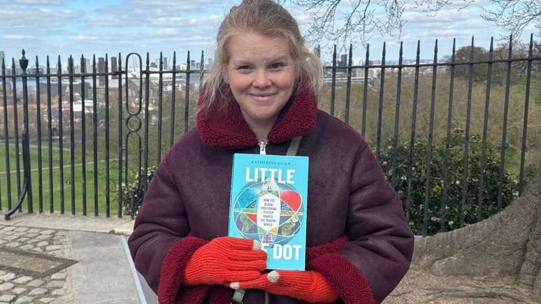 Katherine Dunn, no meridiano de Greenwich, com seu livro
