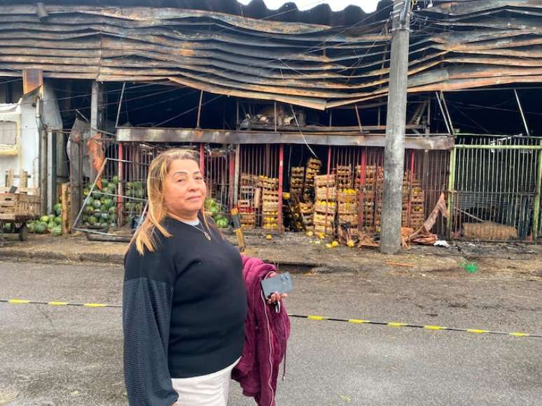 A comerciante Maria Helena em frente dos seus boxes destru&iacute;dos