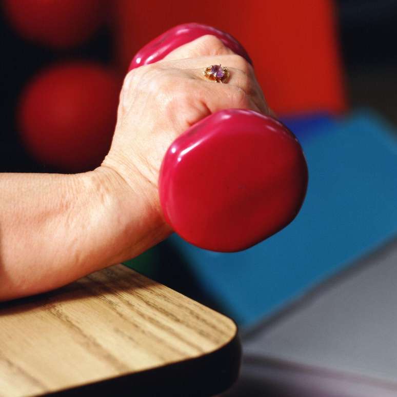 Pulso na borda de uma mesa, com um peso pequeno, fazendo o movimento de extens&atilde;o