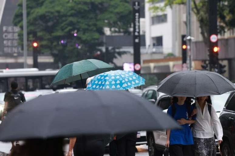 Pedestres caminham com guarda-chuva na Av. Paulista