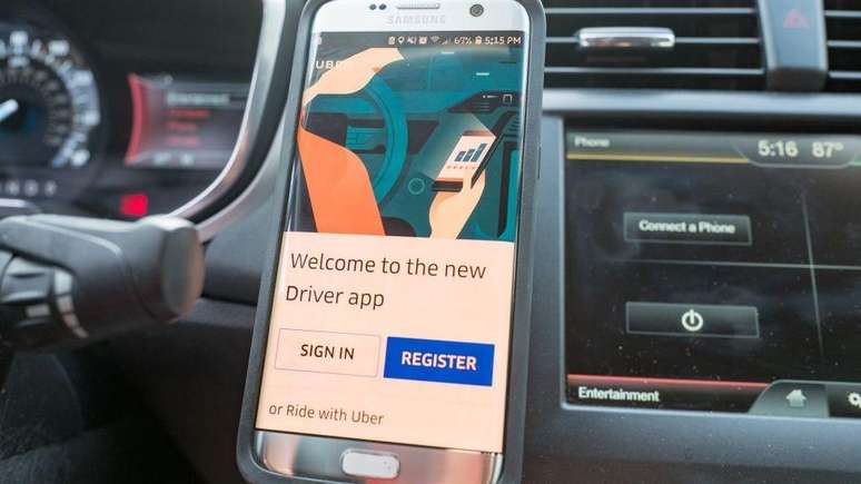 Close-up de um smartphone exibindo o aplicativo para motoristas da Uber, fixado em um suporte magn&eacute;tico no painel de instrumentos, no interior de um ve&iacute;culo da Uber