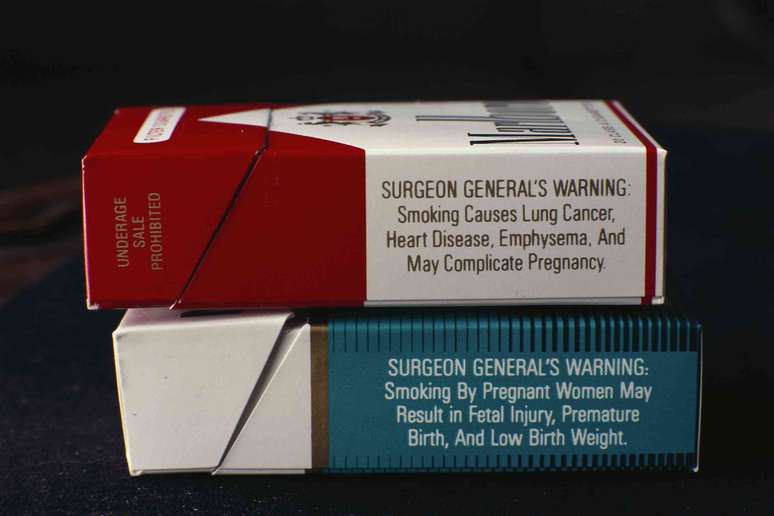 Dois ma&ccedil;os de cigarros exibindo os avisos do Surgeon General sobre os malef&iacute;cios do tabagismo.