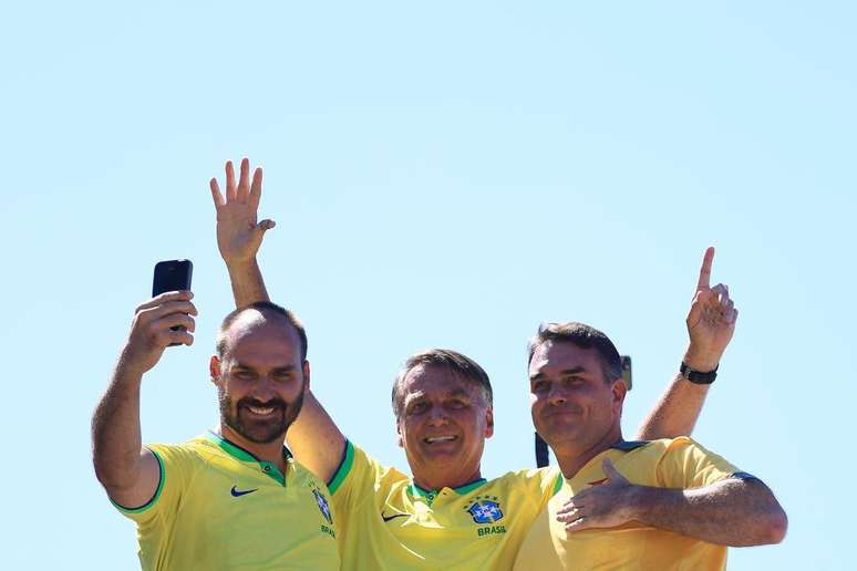 O ex-presidente brasileiro Jair Bolsonaro, acompanhado de seus filhos Eduardo Bolsonaro (E) e Fl&aacute;vio Bolsonaro, acena para seus apoiadores durante um ato na praia de Copacabana em 21 de abril de 2024, no Rio de Janeiro, Brasil.